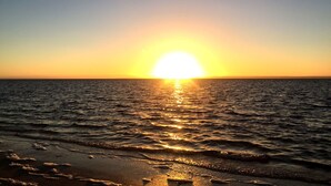 A sunset over the ocean with waves reaching the shore. - KI Caravan Park, Kingscote (Brownlow Ki)