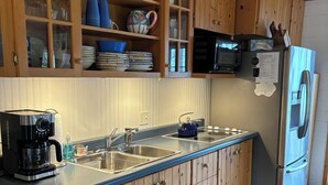 A kitchen with wooden cabinets, a stainless steel refrigerator, and a double sink.