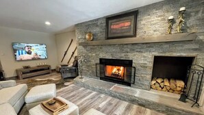 Ein Wohnzimmer mit Kamin, Fernseher und Kaminfeuerkorb mit Dekoration.