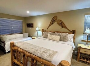 A bedroom with two beds, wooden headboards, a large bed with a white bedspread, and a nightstand with a lamp. - ⭐Mountain Modern Escape⭐INDOOR HOT TUB & FIREPLACE walk to Keystone Slopes (Keystone)