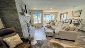 A spacious living room with a stone wall, a leather sofa, a beige sofa, and a large rug. - ⭐Mountain Modern Escape⭐INDOOR HOT TUB & FIREPLACE walk to Keystone Slopes (Keystone)