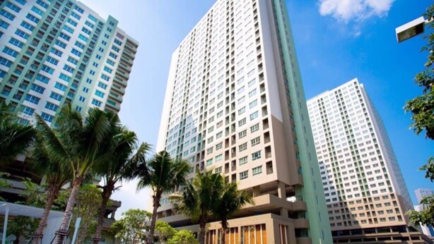 A high-rise building with multiple floors, surrounded by palm trees and greenery. - Lumpini Ville Pattaya Pool Gym (Pattaya)