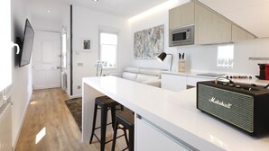 A modern kitchen with a white island, bar stools, a Marshall amplifier, and a microwave above the counter.