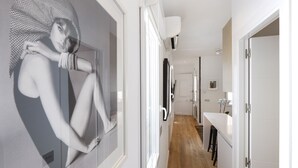 A modern interior with a hallway leading to a bathroom and a kitchen area.