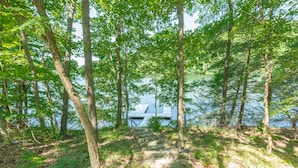 Un escalier en bois menant à une jetée au bord d’un lac, entouré d’arbres.