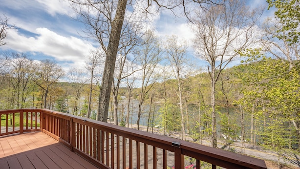 Une terrasse en bois avec une balustrade donnant sur un lac et des arbres.