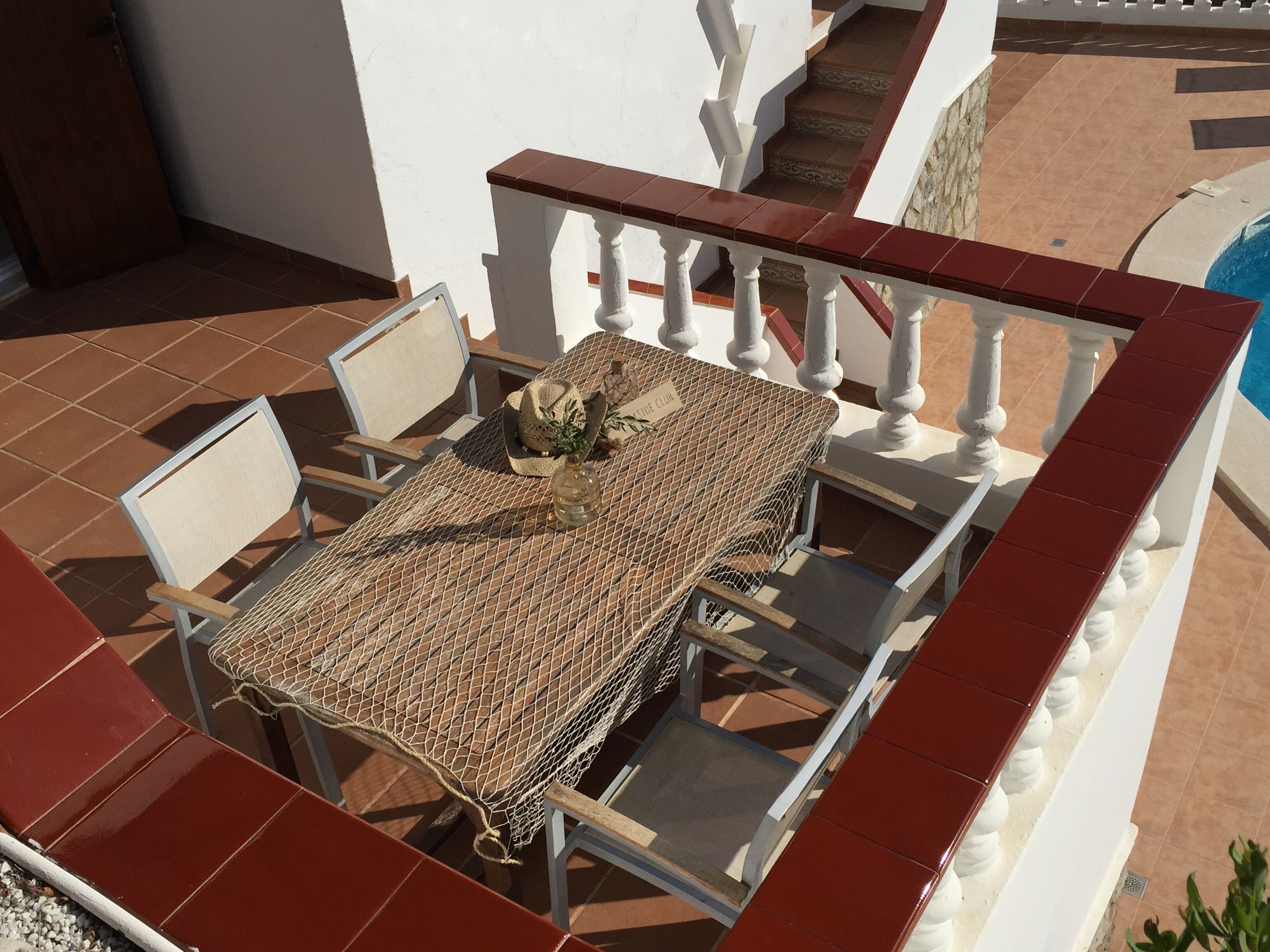 A patio with a table and chairs, a decorative item, and a staircase leading to a pool.