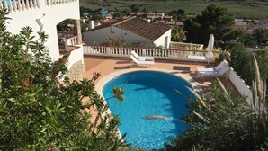 A swimming pool surrounded by a white fence, with a view of the sea and a building in the background. - Luxury Villa, Breathtaking 180° Sea & Sunset views, Private Pool. Fully AC (San Jaime Mediterráneo, Son Bou, Menorca)