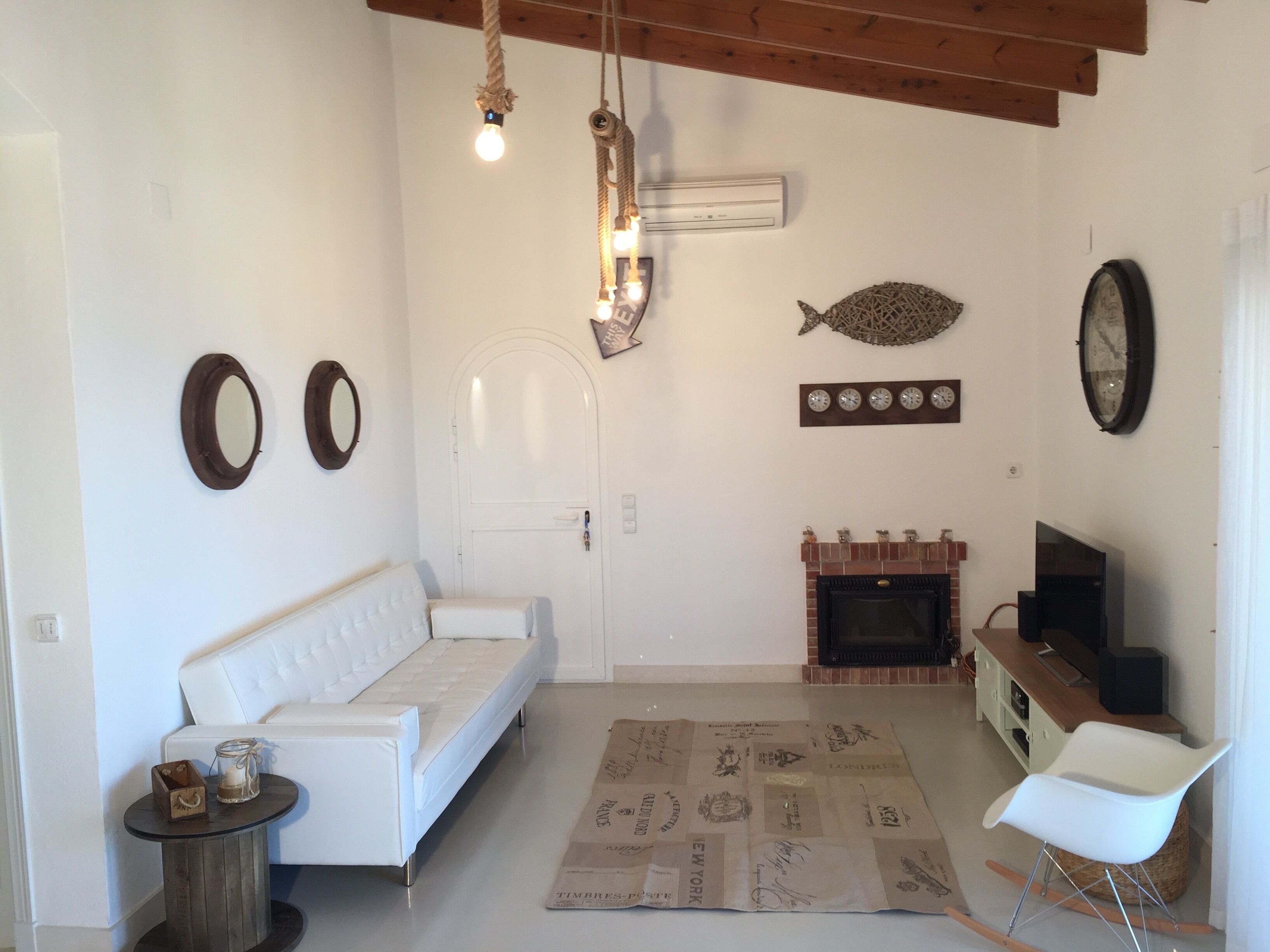 A living room with a white sofa, a small round table, a fireplace, and a white chair.