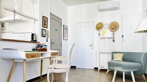 A modern, well-lit room with a white desk, a chair, a blue sofa, and a hanging light fixture.