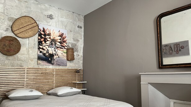 A bedroom with a stone wall, a bed with white bedding, a wooden headboard, and a fireplace.