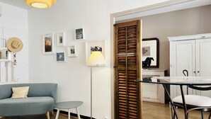 A modern living room with a blue sofa, a small round table, a floor lamp, and a wooden door.