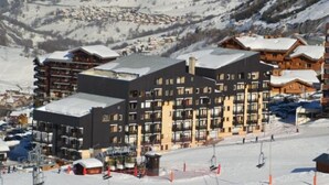 A ski resort with multi-story buildings, ski lifts, and a snowy landscape.