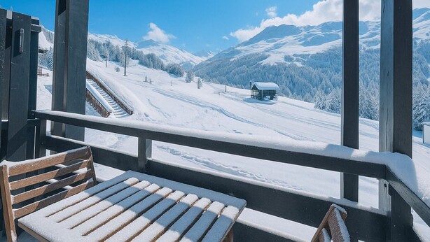 A snow-covered mountain landscape with a wooden bench and a building in the distance.