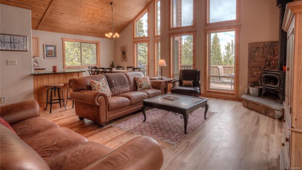 A spacious living room with leather sofas, a coffee table, and a stone fireplace. - Quiet Mountain Retreat in Valley of the Sun (Alma)