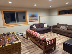 A cozy living room with a foosball table, two sofas, and a wooden bench.