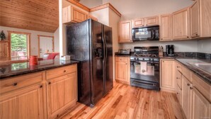 A kitchen with wooden cabinets, a black refrigerator, a microwave, and a stove. - Quiet Mountain Retreat in Valley of the Sun (Alma)