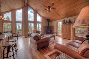 A spacious living area with a fireplace, leather sofas, and a wooden ceiling.