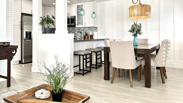 Een moderne keuken met witte kastjes, een roestvrijstalen koelkast en een eethoek met een houten tafel en stoelen.