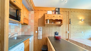A compact kitchen with wooden cabinets, a microwave, a sink, and a coffee maker. - Renovated mountain-style studio for 4 in Les Menuires, east balcony, direct slope access (Les Menuires)