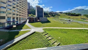 A modern building with multiple floors and a flat roof, surrounded by a well-maintained grassy area and a paved walkway. - Renovated mountain-style studio for 4 in Les Menuires, east balcony, direct slope access (Les Menuires)