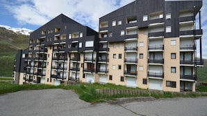 A multi-story building with balconies and a parking area in front. - Renovated mountain-style studio for 4 in Les Menuires, east balcony, direct slope access (Les Menuires)