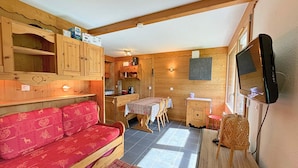 A cozy cabin-style room with a wooden interior, a sofa, a dining table, and a television. - Renovated mountain-style studio for 4 in Les Menuires, east balcony, direct slope access (Les Menuires)