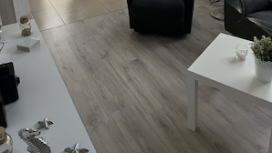 Un salon moderne avec un fauteuil noir, une table basse blanche et un coin repas comprenant une table et des chaises.