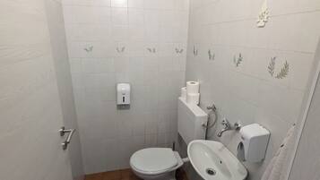 Une petite salle de bain avec des toilettes, un lavabo et un porte-serviettes.