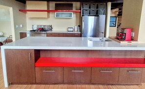 Une cuisine moderne dotée d’un îlot central, d’appareils électroménagers en acier inoxydable et de meubles en bois.
