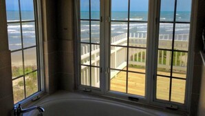 A bathroom with a large window overlooking a wooden deck and the ocean. - Just Steps to the Ocean, Beachfront, House On the Beach, Minutes from Galveston (Freeport)