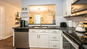 A modern kitchen with white cabinetry, a dishwasher, a sink, and a stove.