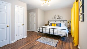 A bedroom with a bed, a bicycle wall decoration, and a yellow curtain.