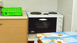 A compact kitchenette with a microwave oven, a green dish rack, and a table with a floral tablecloth. - Apartment Danai is situated near the Centre of Ermoupolis (Ano Siros)