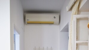 A narrow hallway with a white door, a tiled floor, and a white air conditioning unit above the door. - Apartment Danai is situated near the Centre of Ermoupolis (Ano Siros)