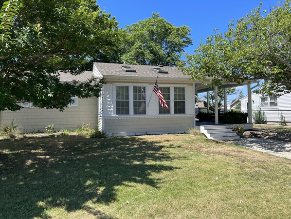 Einbungalow mit überdachter Veranda, einem kleinen Garten und einer amerikanischen Flagge.