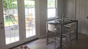 Een eethoek met een tafel gedekt voor vier personen, een schuifdeur naar een terras en een witte deur.
