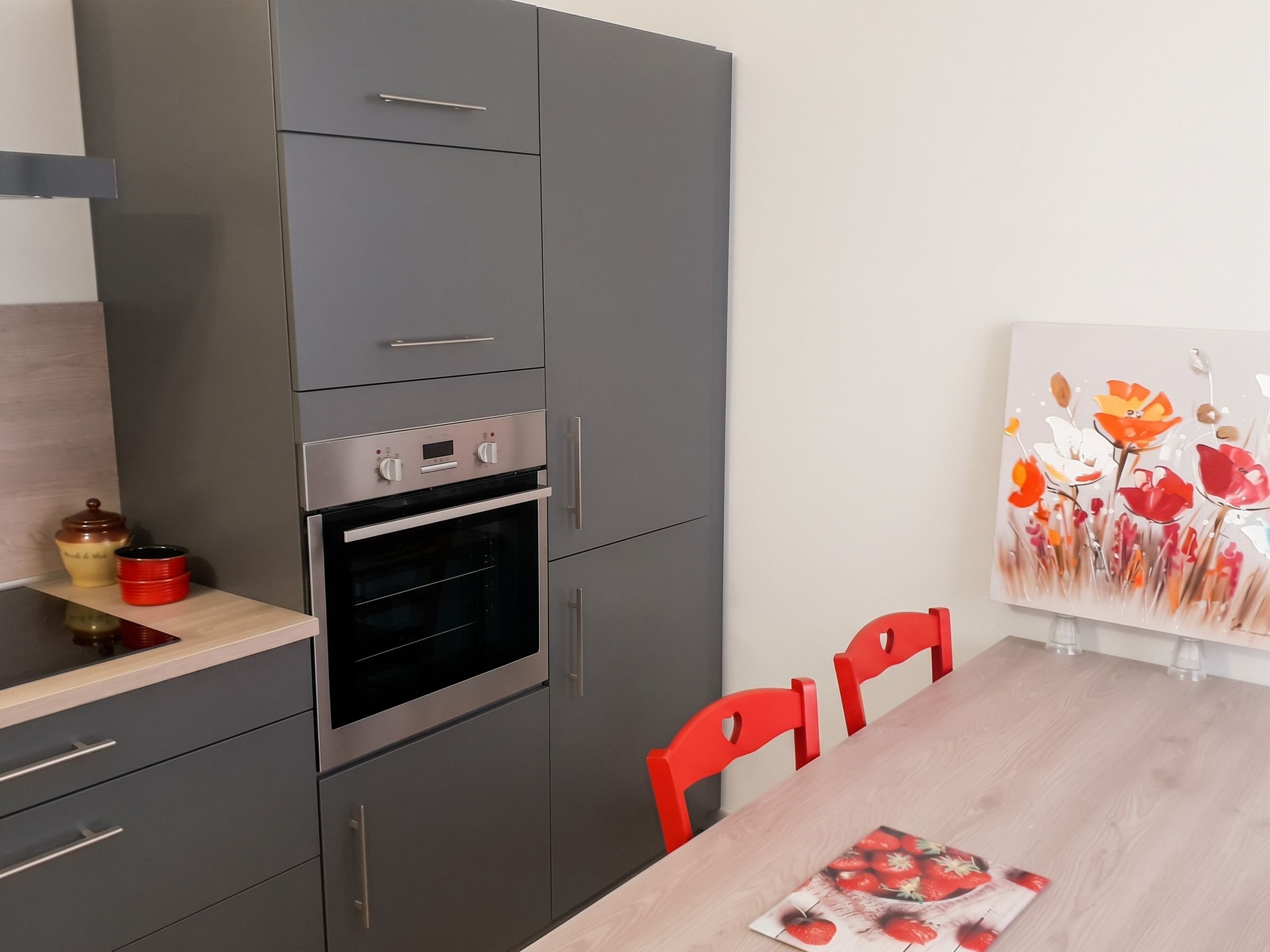 Una cocina moderna con horno integrado, una mesa de comedor con sillas y un cuadro en la pared.