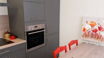 Una cocina moderna con horno integrado, una mesa de comedor con sillas y un cuadro en la pared.