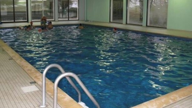 An indoor swimming pool with clear water, metal pool ladders, and large windows along the walls. - Homerez - Apartment – Métabief (Métabief)