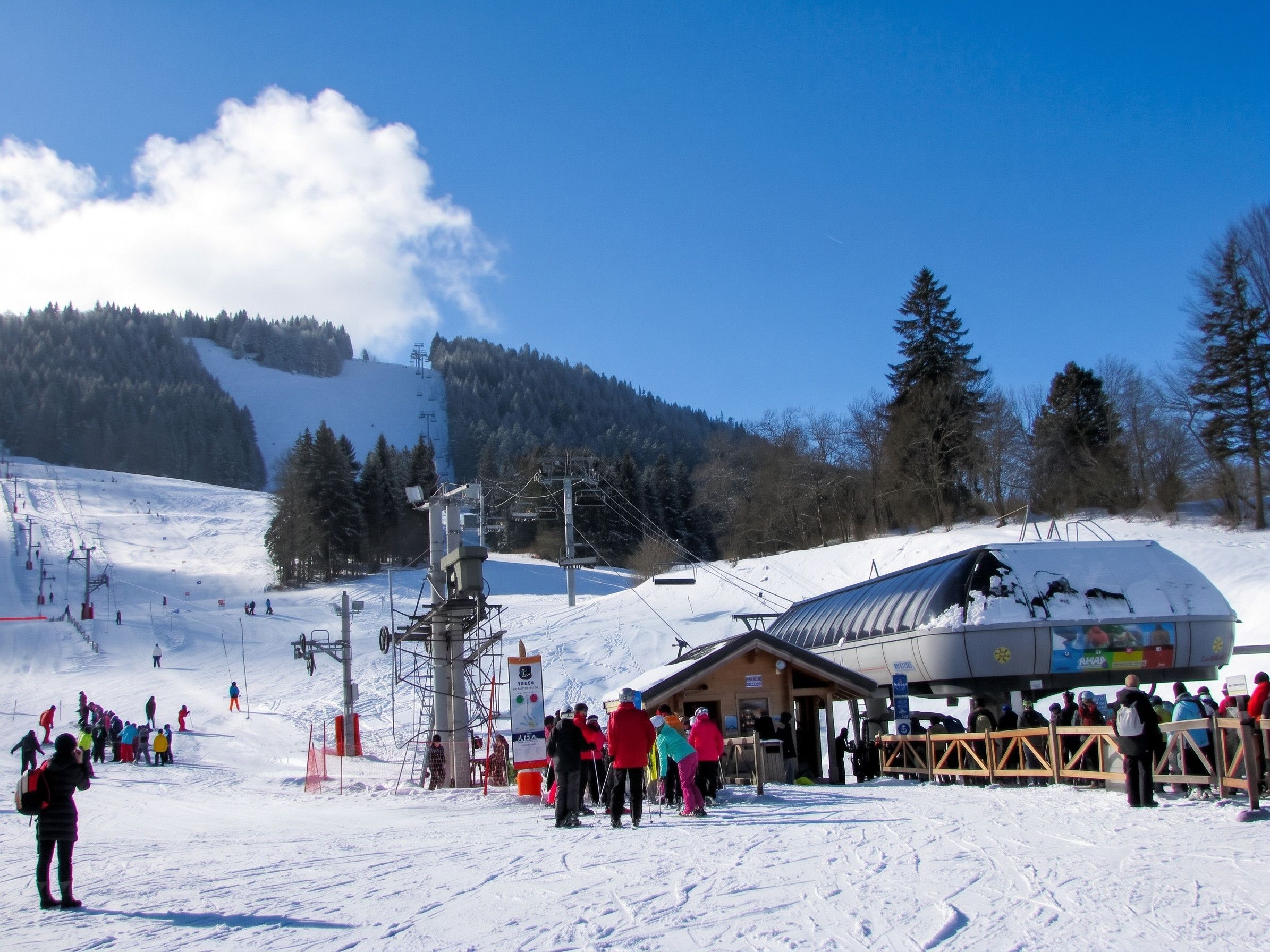 A ski resort with a ski lift, a lodge, and a snowy landscape.