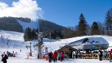 A ski resort with a ski lift, a lodge, and a snowy landscape.