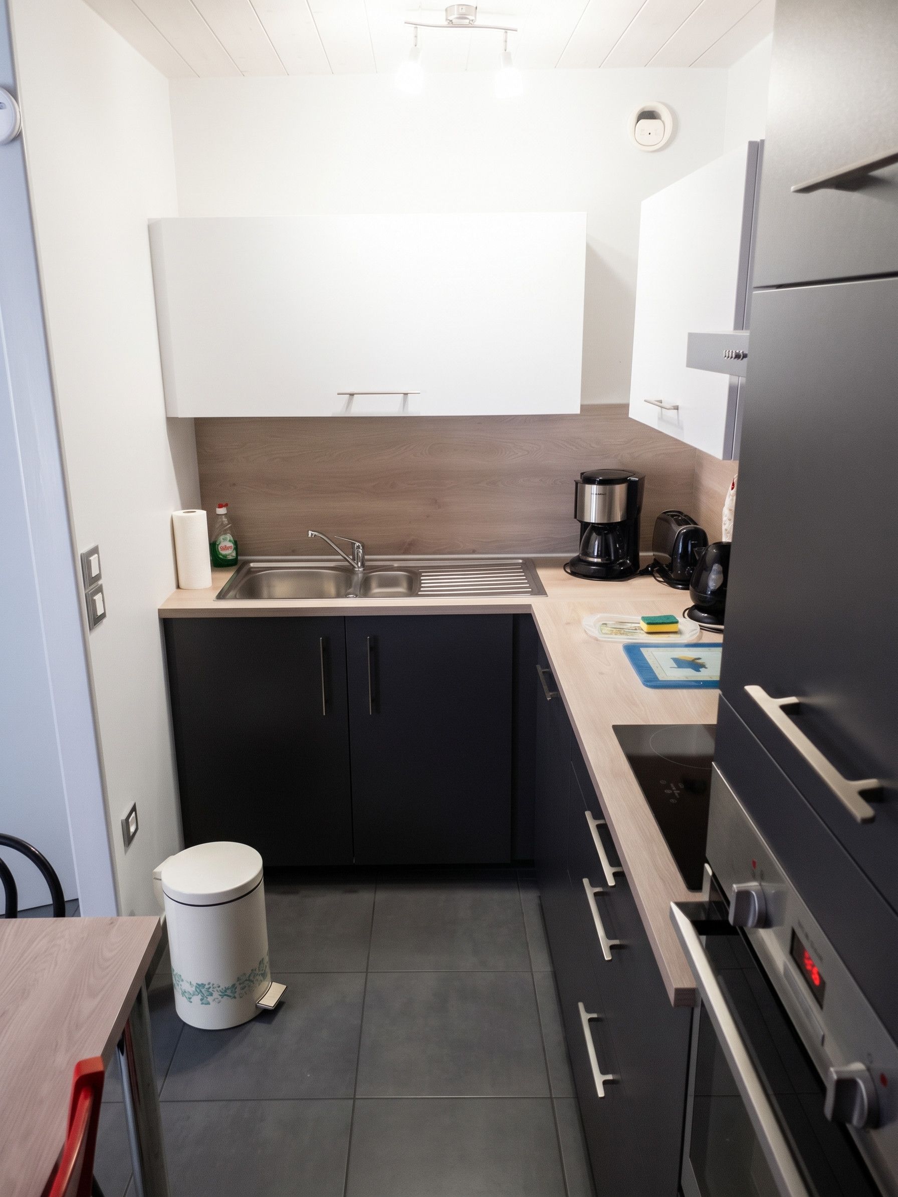 A compact kitchen with a sink, a coffee maker, a toaster, and a refrigerator.
