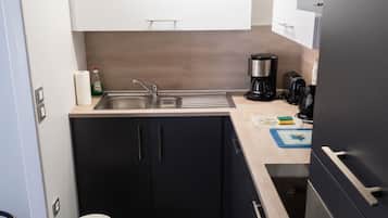 A compact kitchen with a sink, a coffee maker, a toaster, and a refrigerator.