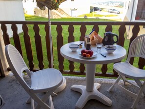 A balcony with a table set for two, featuring a pitcher, bowls, a jar, and a plate of fruit. - Homerez - Apartment – Métabief (Métabief)
