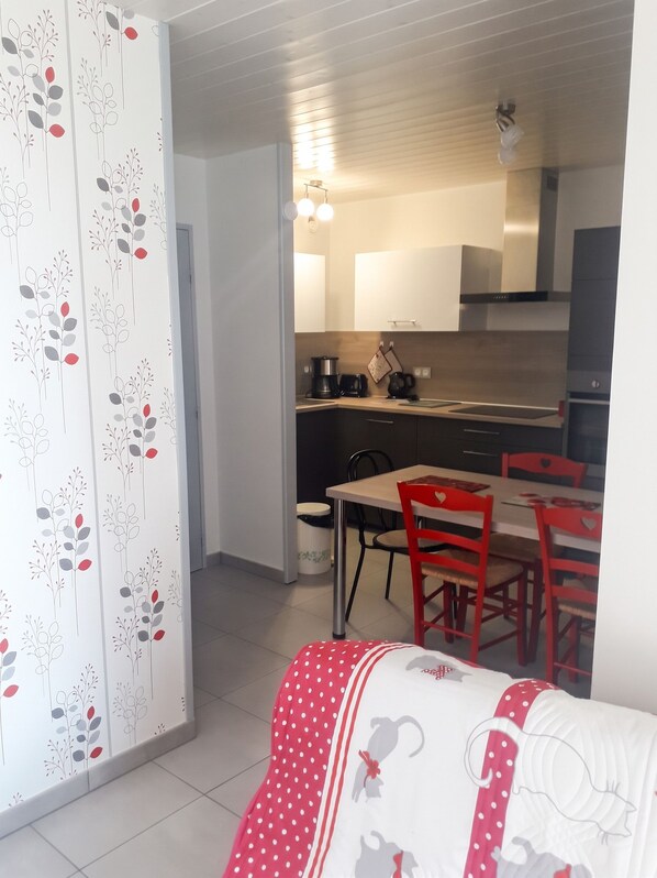 A compact living space with a kitchenette, a dining area with red chairs, and a patterned curtain. - Homerez - Apartment – Métabief (Métabief)
