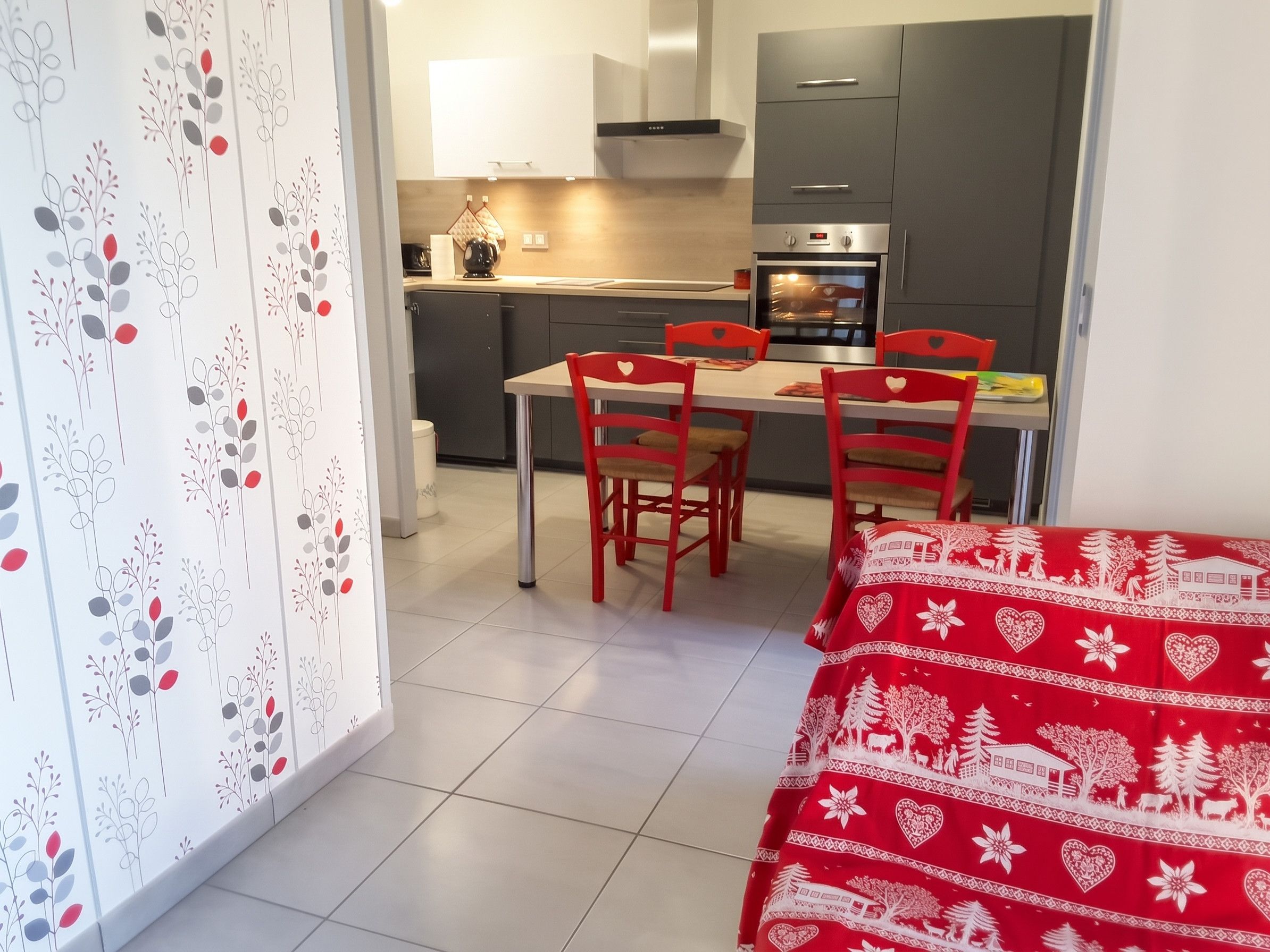 A compact kitchen with a dining area, featuring a table with four chairs, a refrigerator, an oven, and a microwave.