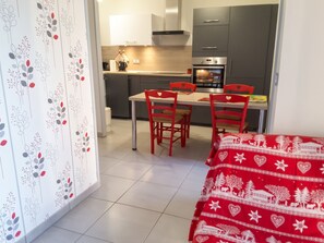 A compact kitchen with a dining area, featuring a table with four chairs, a refrigerator, an oven, and a microwave. - Homerez - Apartment – Métabief (Métabief)