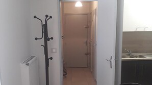 A narrow hallway with a coat rack, a door leading to a room, and a kitchen area with a sink. - Homerez - Apartment – Métabief (Métabief)