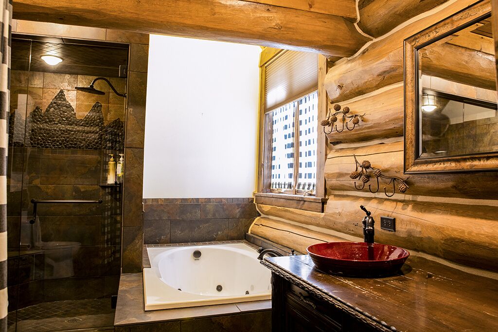 Un baño con bañera, cabina de ducha con mampara de vidrio y ventana con vistas a edificios.